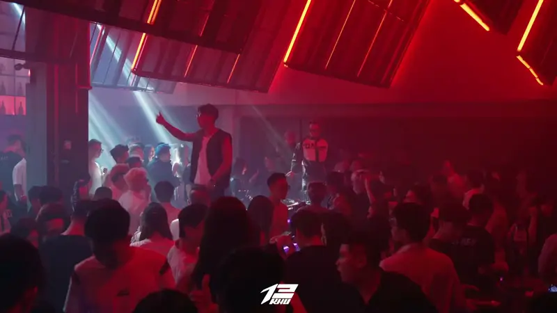 Dải đèn đỏ chạy trên khung trần KHU 13, nghệ sĩ đứng trên bốt DJ giữa đám đông